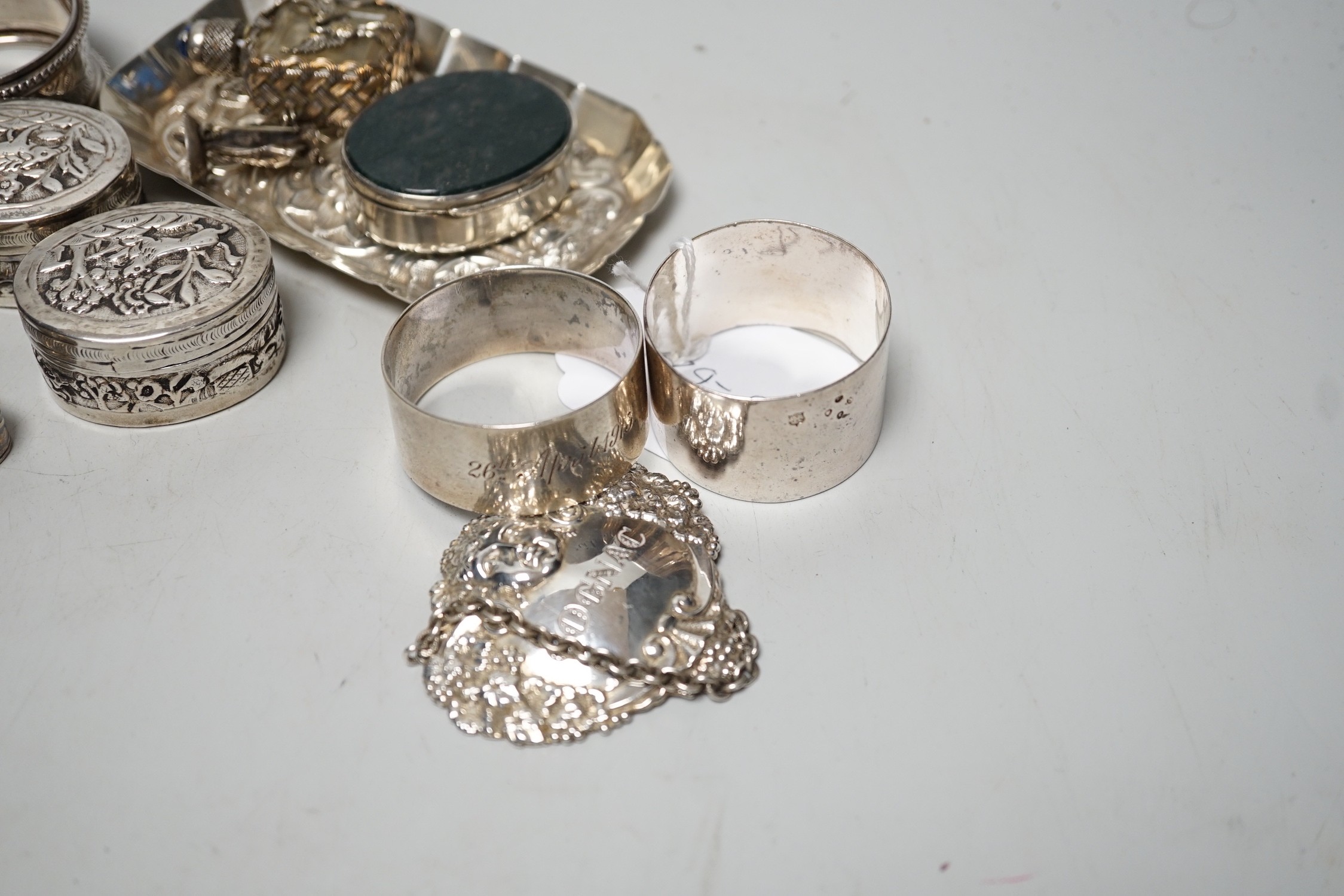 Sundry small silver including four assorted napkin rings, mounted bible, butter knife, pin tray, wine label etc. together with two white metal oval pill boxes, a moss agate mounted oval pill box and scent bottle.